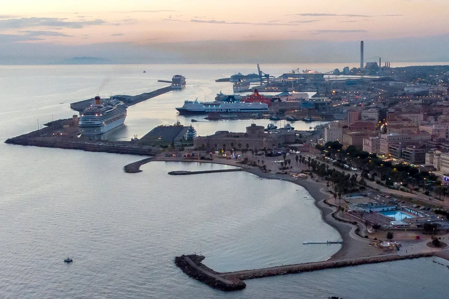 Luftaufnahme des Hafens Civitavecchia mit mehreren Kreuzfahrtschiffen an den Piers bei Abenddämmerung
