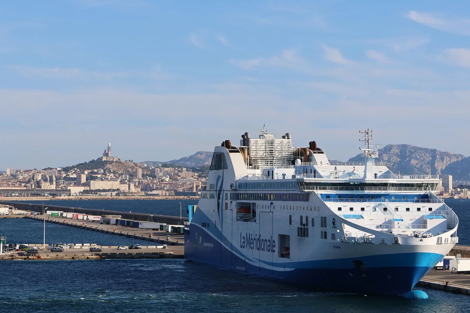 Weißes Kreuzfahrtschiff der Reederei La Méridionale am Liegeplatz im Hafen von Marseille mit Stadtpanorama