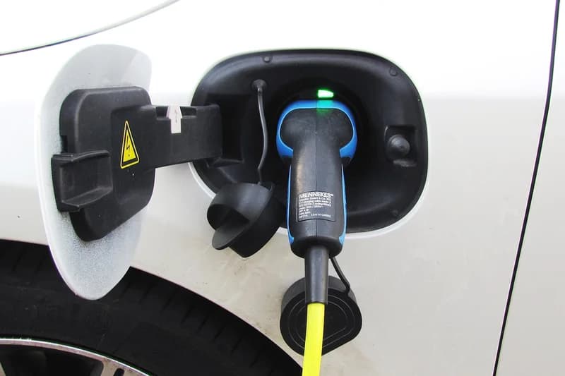 Ladestecker eines Elektrofahrzeugs steckt in der Ladebuchse mit offenem Klappenbereich und grünem Kontrolllicht